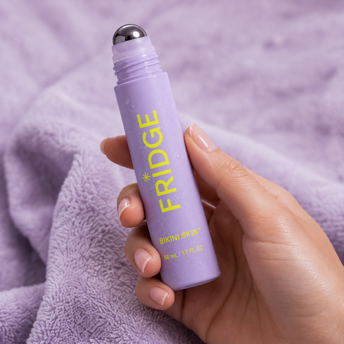 FRIDGE Bikini Skin cooling roller held in hand against lavender towel